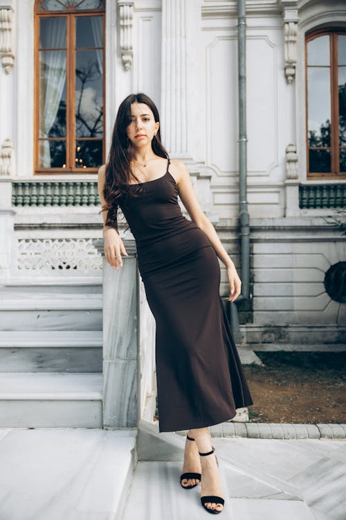 A woman in a brown dress posing on steps