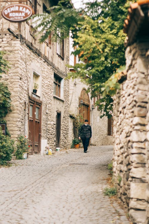 Elderly Man Walking Down Cobblestone Street