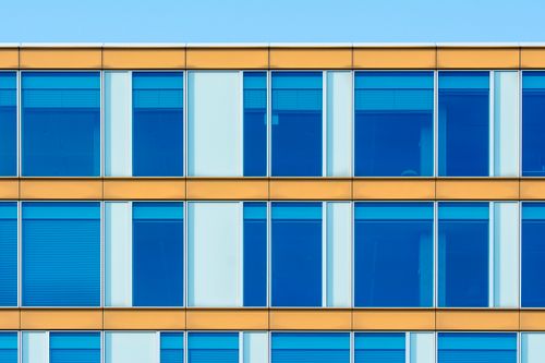 Free Contemporary office building facade showcasing blue windows and yellow structure. Stock Photo