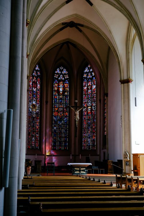 Free An interior view of a Gothic cathedral featuring stunning stained glass windows and wooden pews. Stock Photo