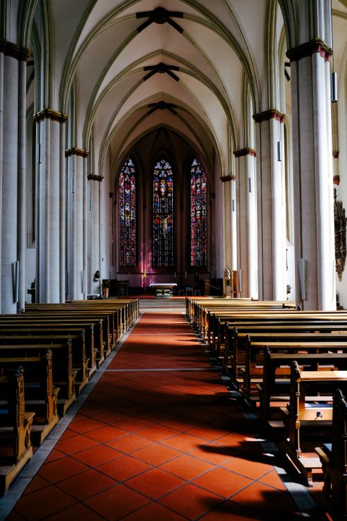 Free Empty cathedral interior showcasing gothic architecture and vibrant stained glass windows. Stock Photo