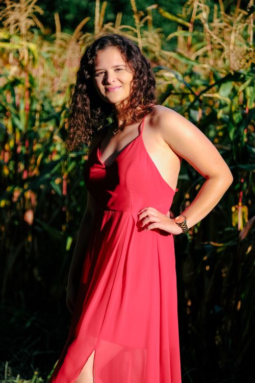 Free Elegant portrait of a woman with curly hair in a red dress standing outdoors. Stock Photo