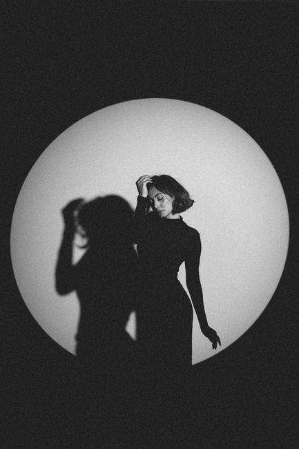 Monochrome fashion portrait of a woman posing in spotlight.