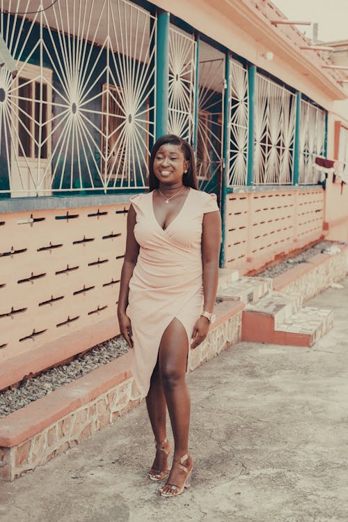 Young Woman in a Dress and Heels Standing on a Sidewalk 