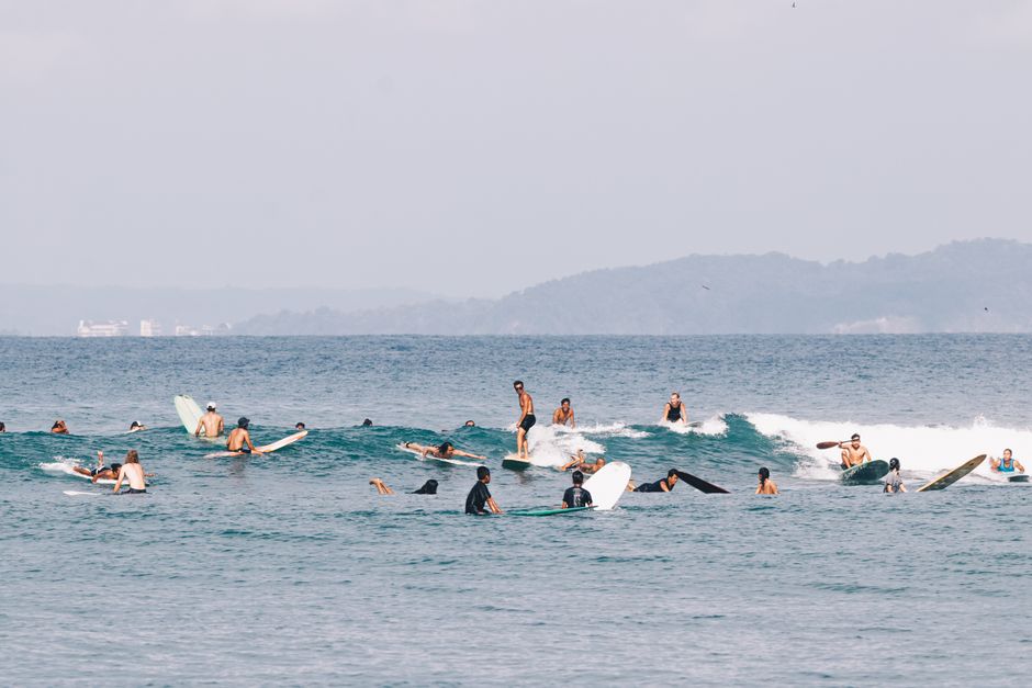 A group of surfers catching waves on the coast of West Java, Indonesia.