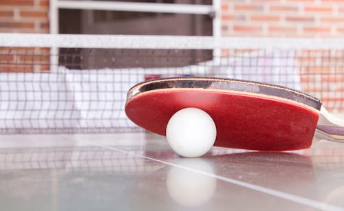 Free White Pingpong Ball Beneath Red Table Tennis Paddle Stock Photo