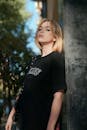 Young Woman in a Black T-shirt Standing against a Wall Outside