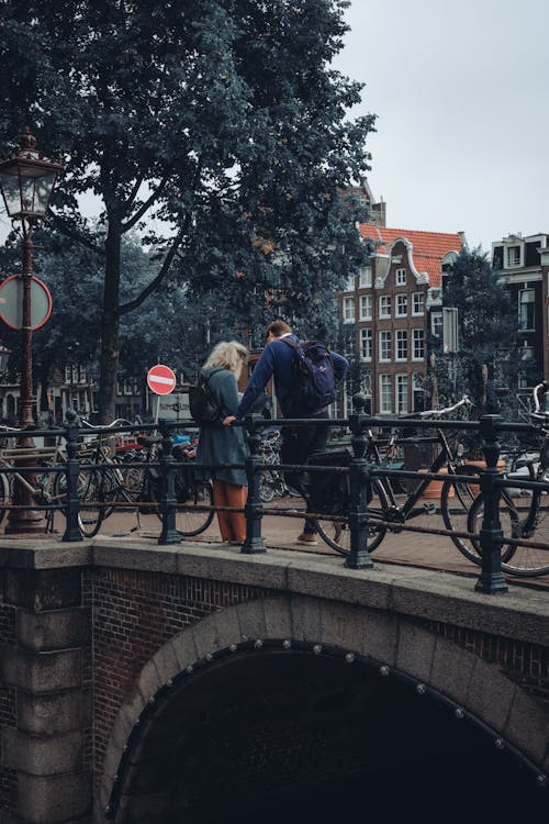 Candid Photo of Pedestrians Standing on a Bridge with Bicycles in Amsterdam, the Netherlands 