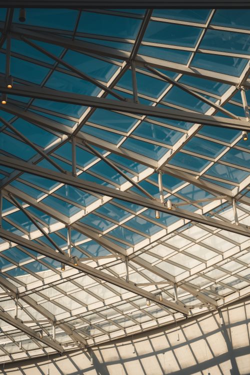 Free Sunlight streaming through a modern architectural glass ceiling showcasing intricate grid patterns. Stock Photo