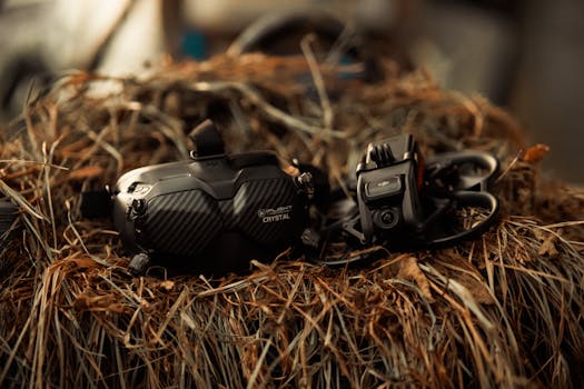 Close-up of FPV drone and goggles placed on a rustic straw surface, showcasing technology in nature.