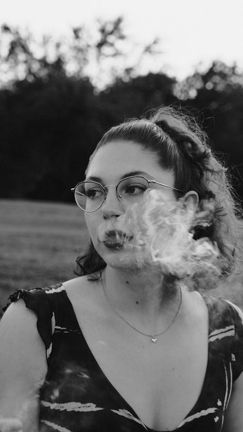 Woman in Sleeveless Dress Exhaling Cigarette Smoke