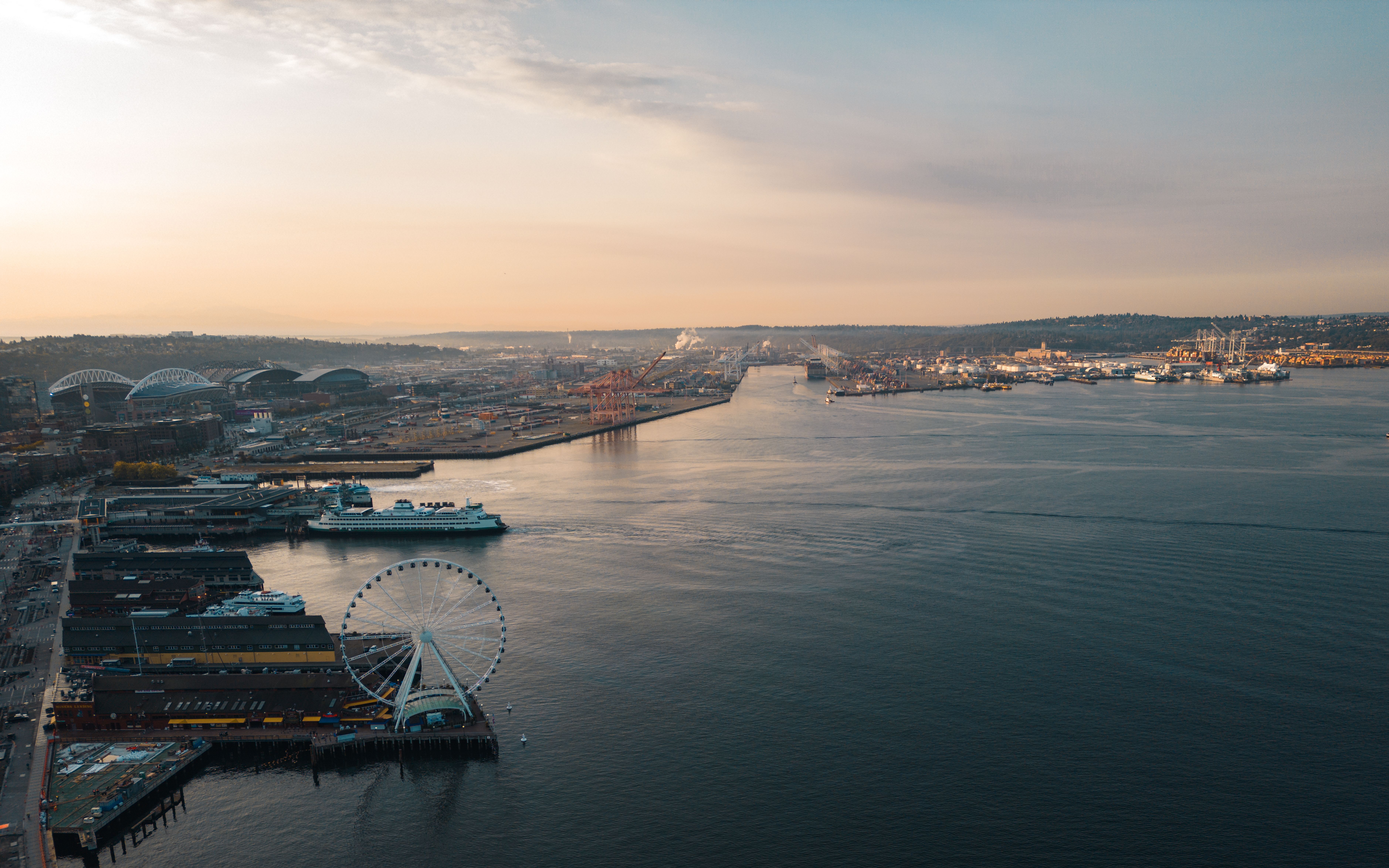 Scenic aerial view of Seattle waterfront with ferris wheel at sunset, showcasing urban landscape.