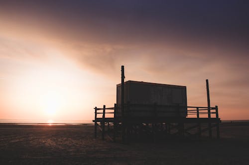 Silhouetted Wooden Hut on a Beach at Sunset