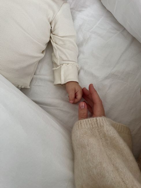 Cozy scene of a mother gently holding her baby's hand, conveying warmth and care.