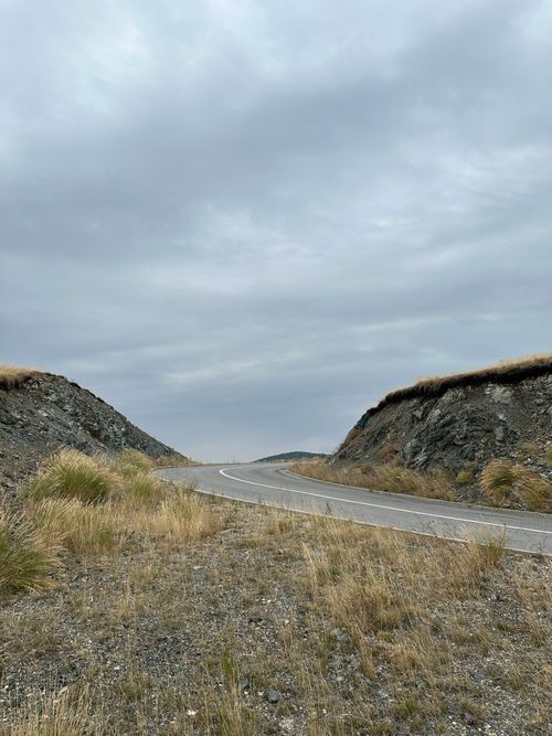 Free A curved road cuts through a barren, rocky landscape under an overcast sky. Stock Photo
