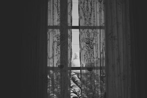 Black and White Photo of Lace Curtains Hanging in a Window 