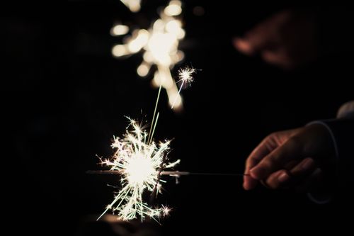 Free Close-up of hands holding sparklers, illuminating a night-time celebration. Stock Photo