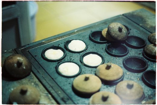 Close-up of Vietnamese cakes being prepared in a rustic kitchen setting with traditional cookware.