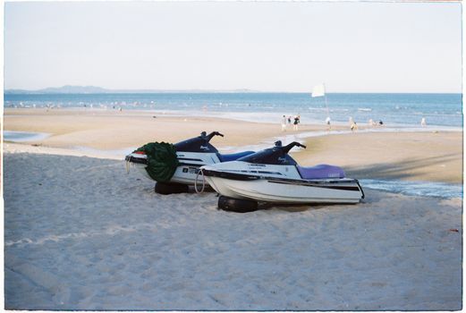 Jet skis on a sandy beach with the ocean in the backdrop at sunrise, perfect for adventure lovers.