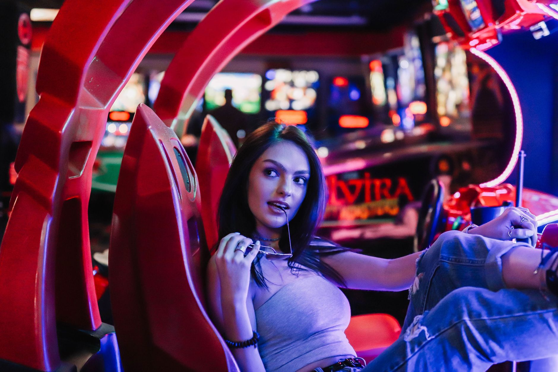 Woman in casual attire enjoying leisure time at a colorful arcade, exuding a relaxed vibe.