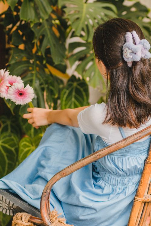 Free Woman seated in a lush garden holding pink flowers, exuding a serene vibe. Stock Photo