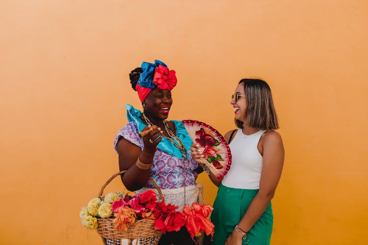 Two Women Talking And Laughing Against An Orange Background