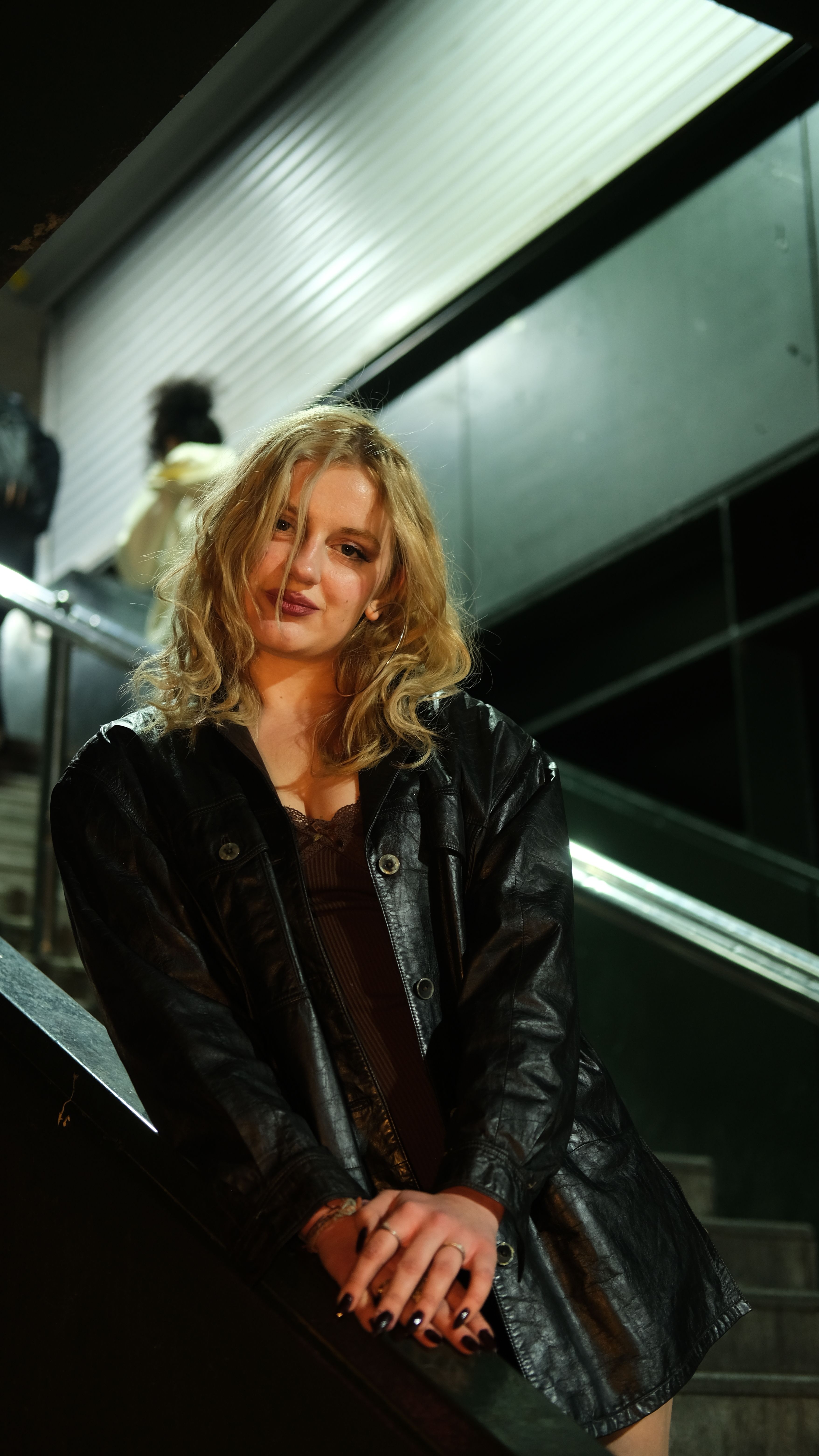 Young Woman in a Leather Jacket Standing near the Stairs · Free Stock Photo