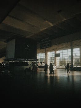 Low-lit view of travelers moving through a bustling station, capturing a sense of transit and waiting.