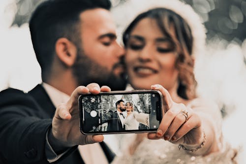 Newlyweds Taking a Selfie with Their Phone while Kissing