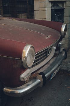 Close-up of an old vintage car parked on an urban street, showcasing its retro design.