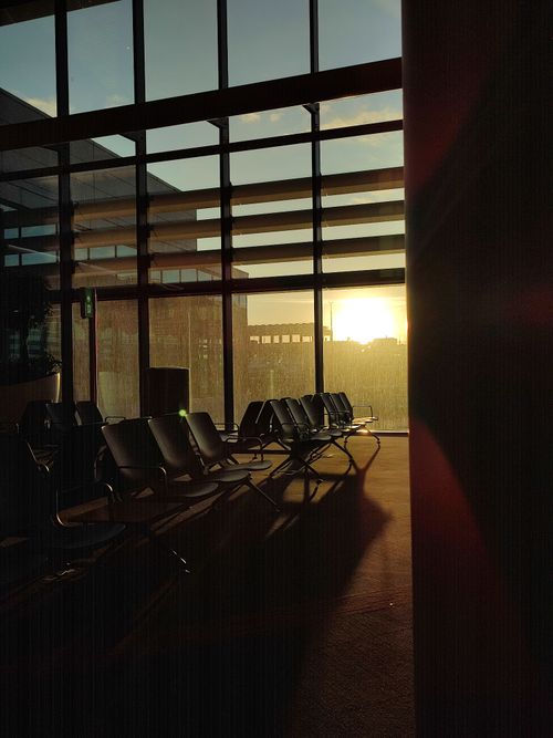 Free Empty airport lounge chairs by large windows during sunrise creating a peaceful ambiance. Stock Photo
