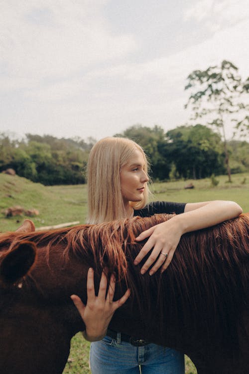 Blonde Woman Embracing Chestnut Horse on Farm