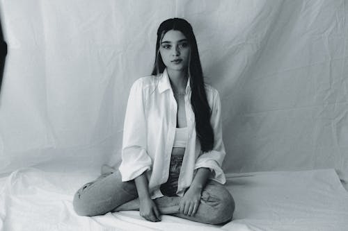 Black and White Photo of a Young Woman in a Casual Outfit Sitting on the Floor 