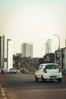 An urban street scene capturing city traffic against a backdrop of modern skyscrapers and buildings.