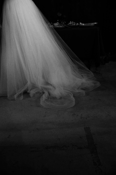 A hauntingly beautiful white wedding gown captured against a dark background.