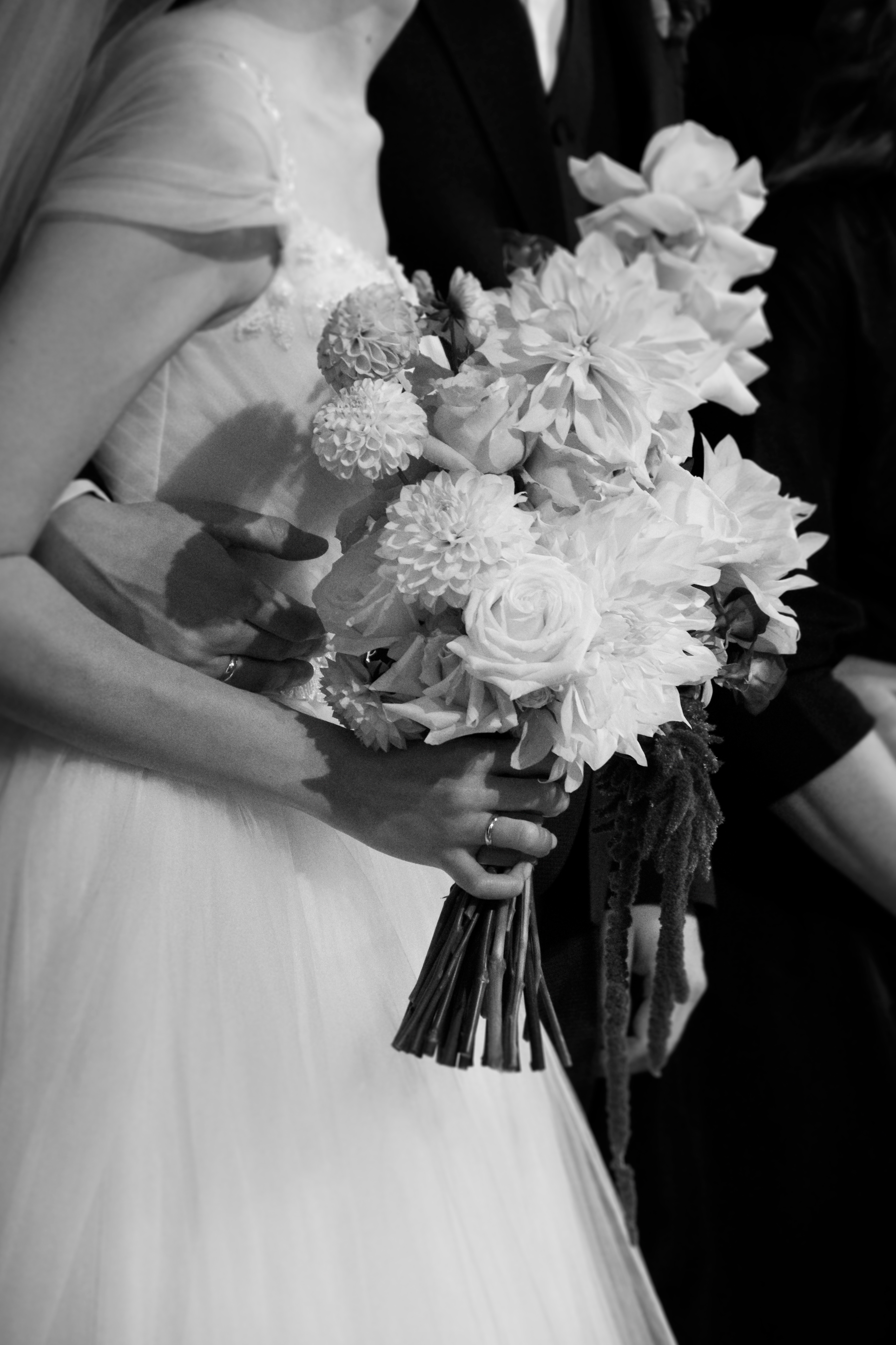 A loose ceremony arch of grasses and dahlias on a wooden frame.