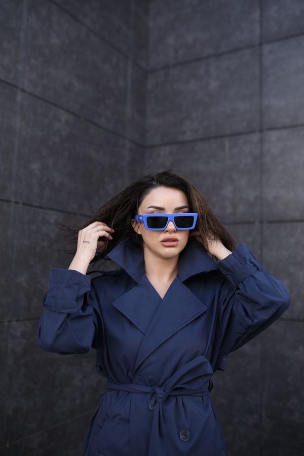 Model in a navy blue trench coat with sunglasses