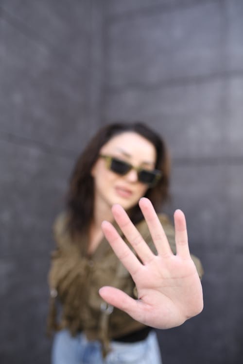 Young Brunette Woman in Sunglasses Showing her Palm to the Camera