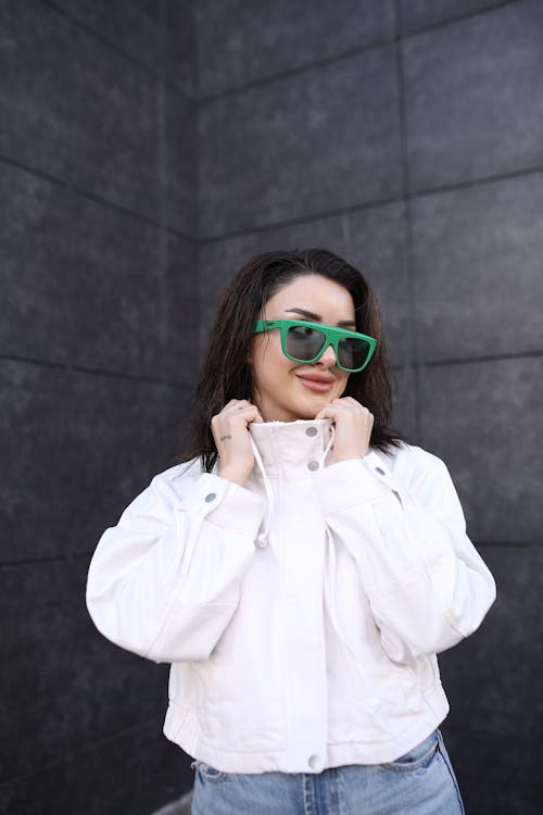 Free Young Brunette Woman in Green Sunglasses Holding her White Jacket Stock Photo