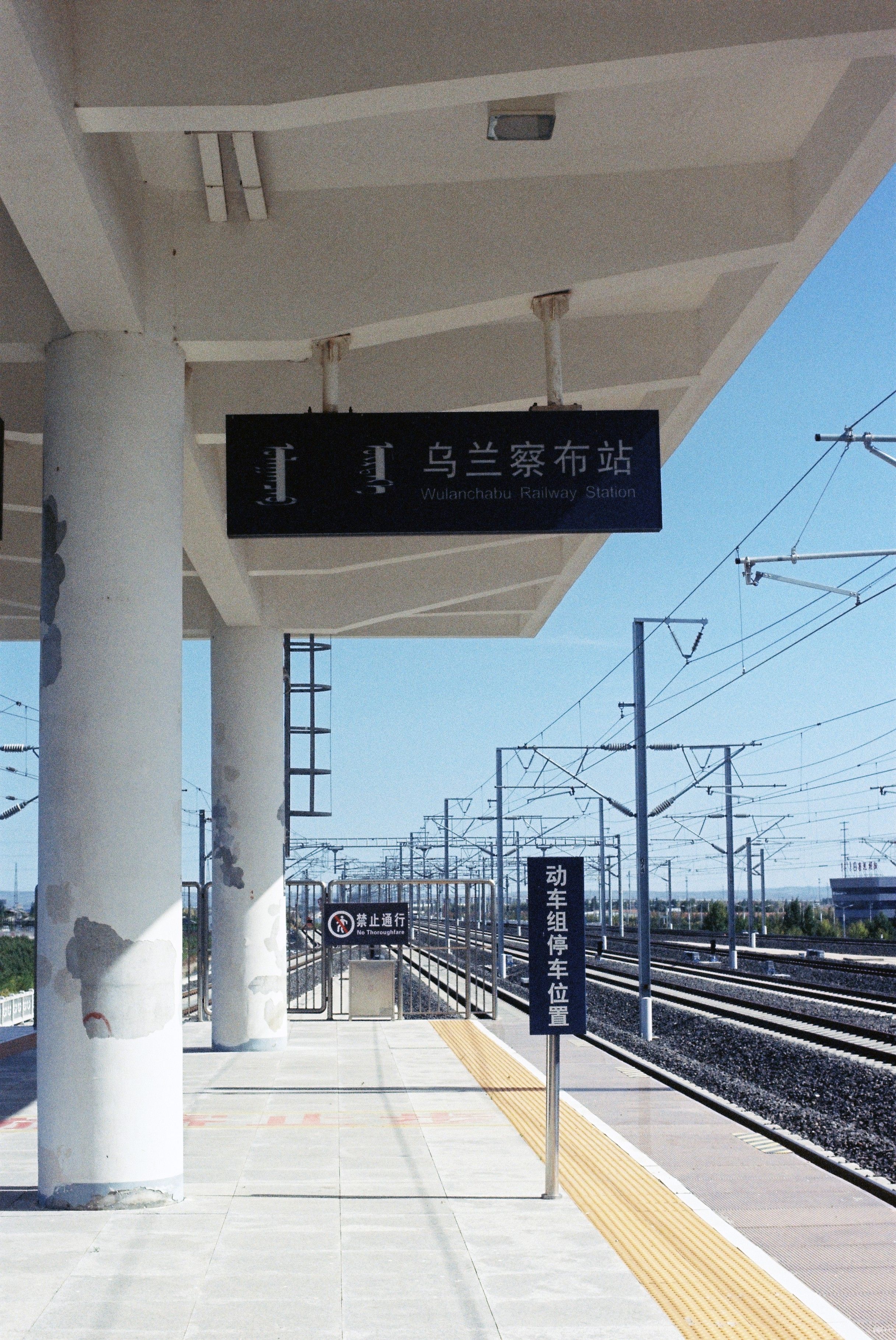 Empty railway station in Wulanqab, China with visible tracklines and signage.