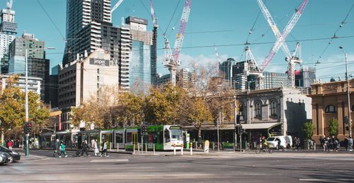 Free Contemporary urban view in Melbourne with trams, skyscrapers, and lively street activity. Stock Photo