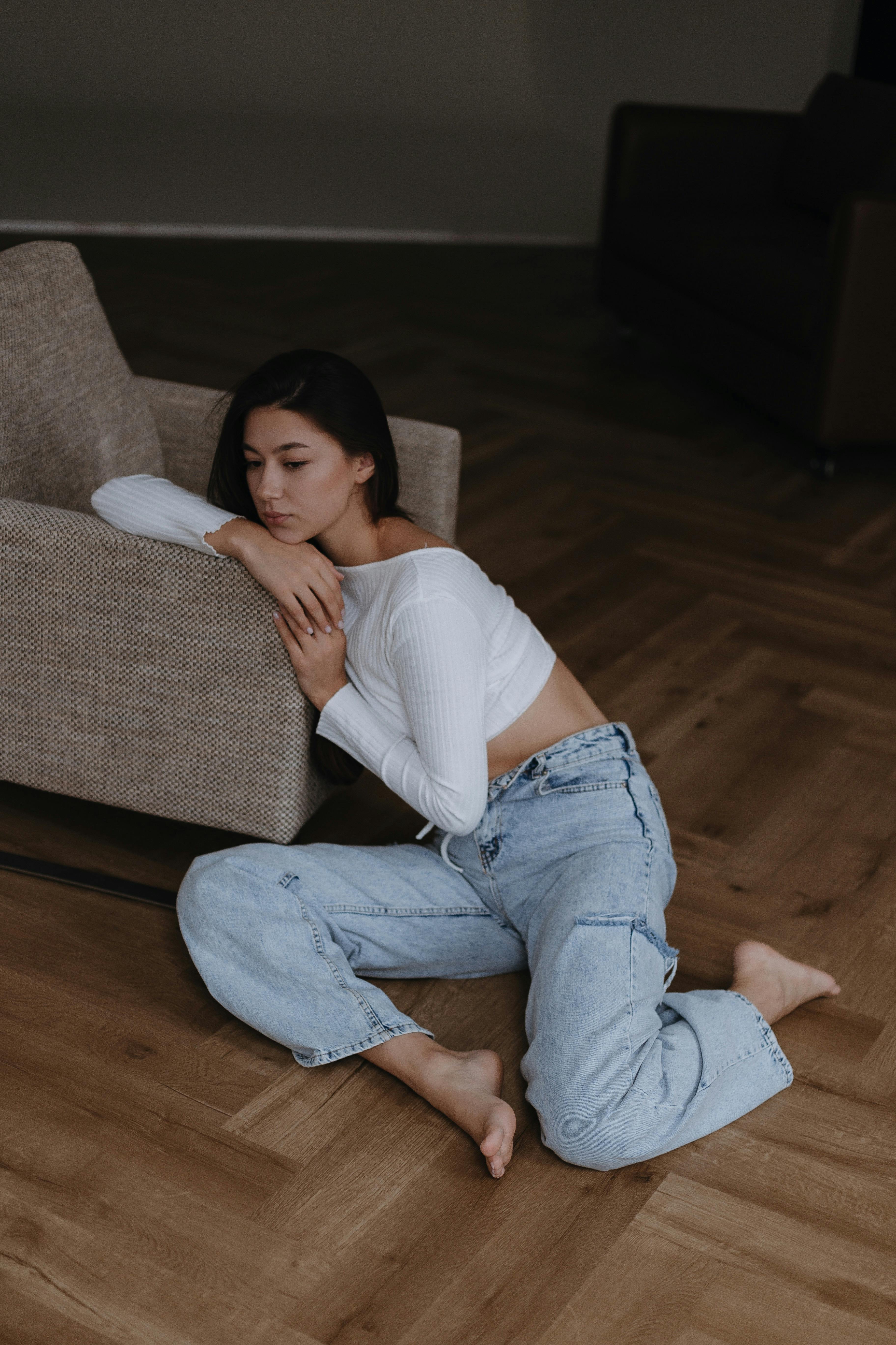 Barefoot Brunette Woman in White Knit Top and Blue Jeans Sitting