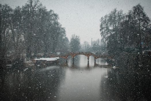 A stunning winter scene of a snow-covered bridge over a calm river in Srinagar.