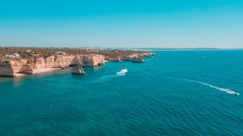 Free A stunning aerial view of jagged cliffs along a pristine coastline with clear blue waters. Stock Photo