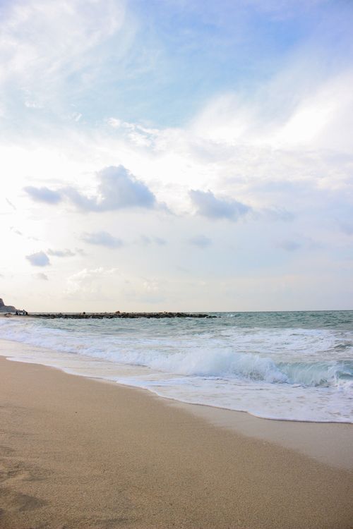 Free Calm beach with gentle waves and a clear sky, ideal for a relaxing summer day. Stock Photo