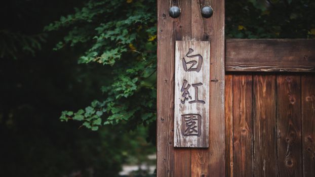 Close-up of a wooden sign with Japanese characters in a garden in Wrocław, Poland.