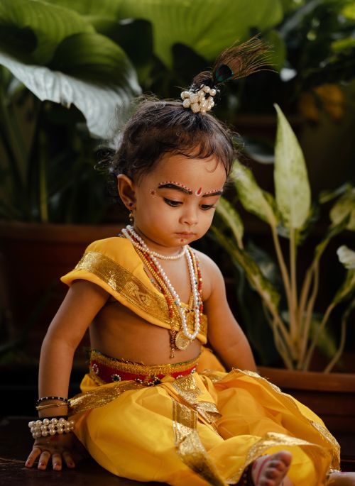 Free A baby dressed in traditional Indian attire with makeup sitting indoors. Stock Photo