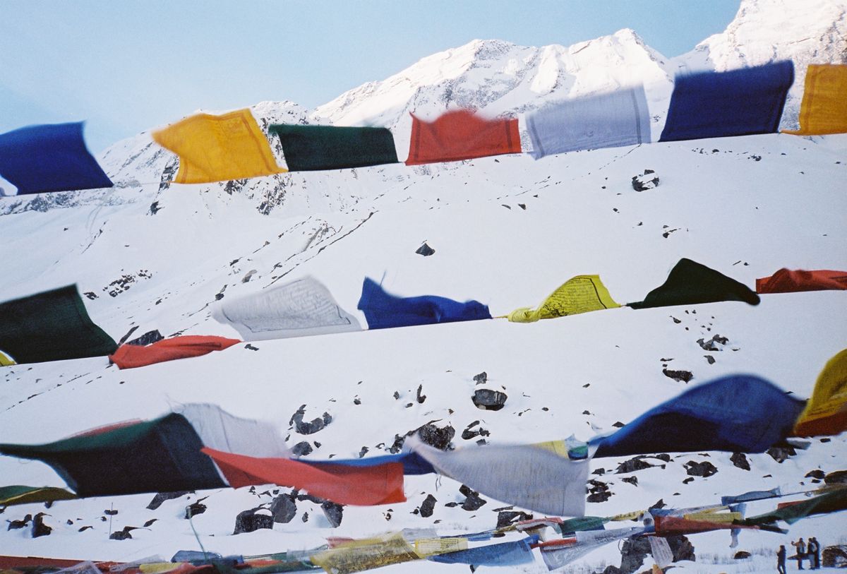 Colorful prayer flags flutter in the snowy mountains of Annapurna, Nepal, creating a vibrant scene.