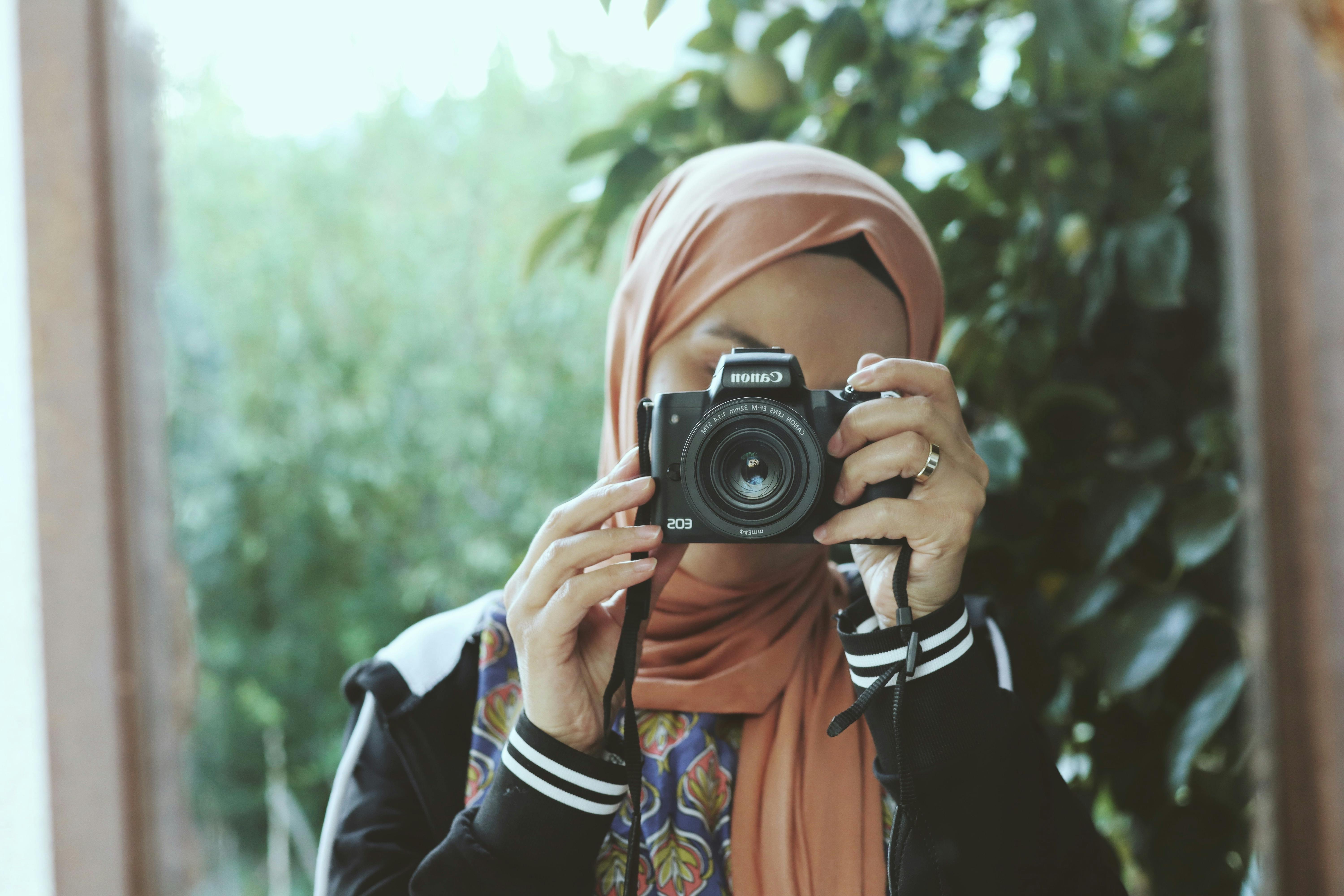 woman in hijab taking pictures in mirror