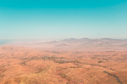 A stunning aerial view of the barren, eroded landscape in Tuineje, Spain, showcasing vast desert and mountain vistas.